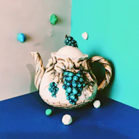 a teapot with grapes on a blue background