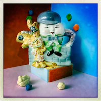 a ceramic figurine is sitting on top of a brick